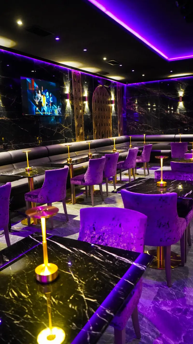 La salle du Purple Lounge : fauteuils en velours violet et tables en marbre